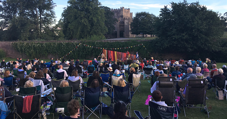 outdoor performance in the grounds of Raby Castle with crowd sat watching